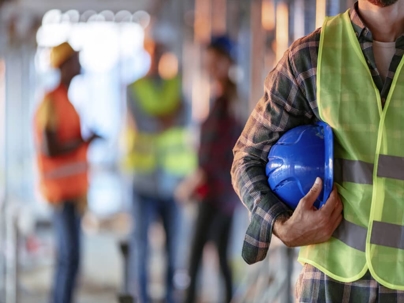 an industrial worker holding blue construction hat