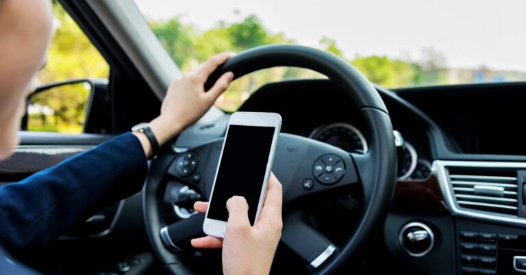 Person behind wheel looks at phone.