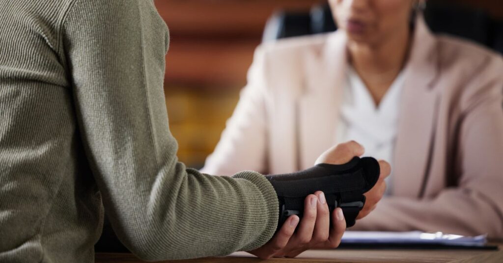 Man with brace on wrist sits across from woman.