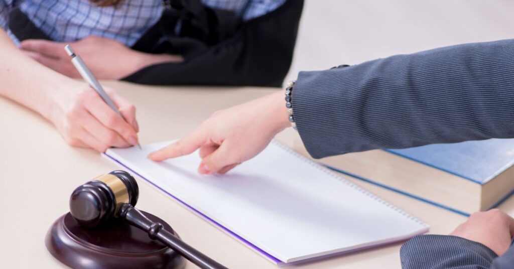 Hand points place on document for signature.