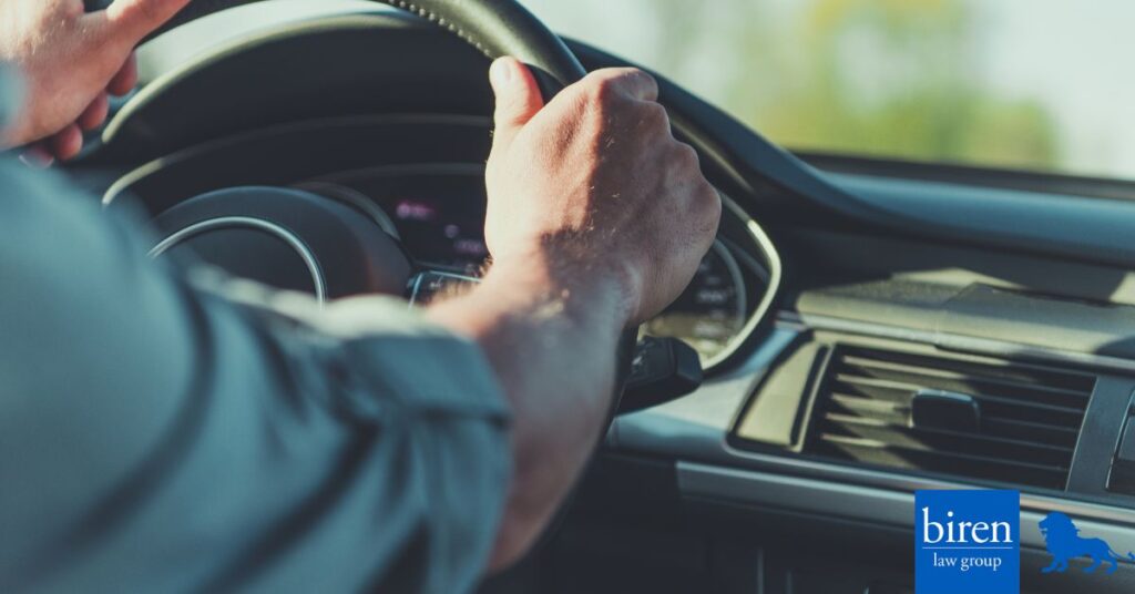 Hands holding steering wheel of vehicle.