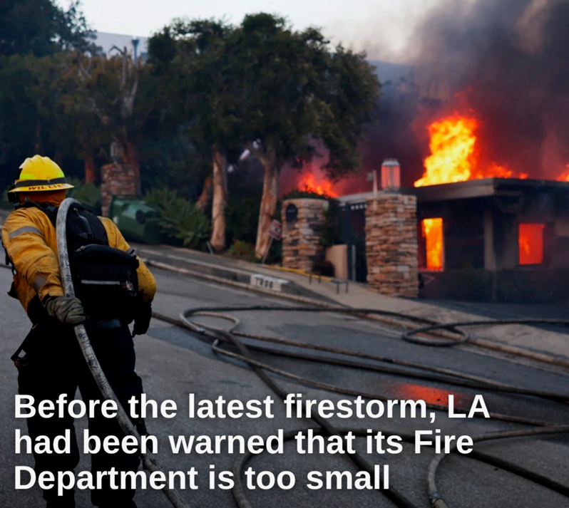 a firefighter walking on a road next to a house on fire